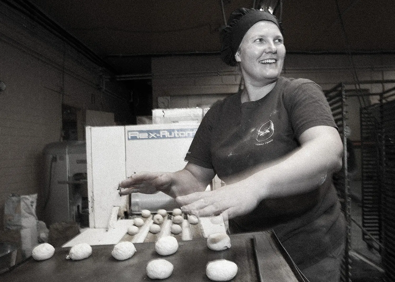 happy bakery employee operatig a bun making machine