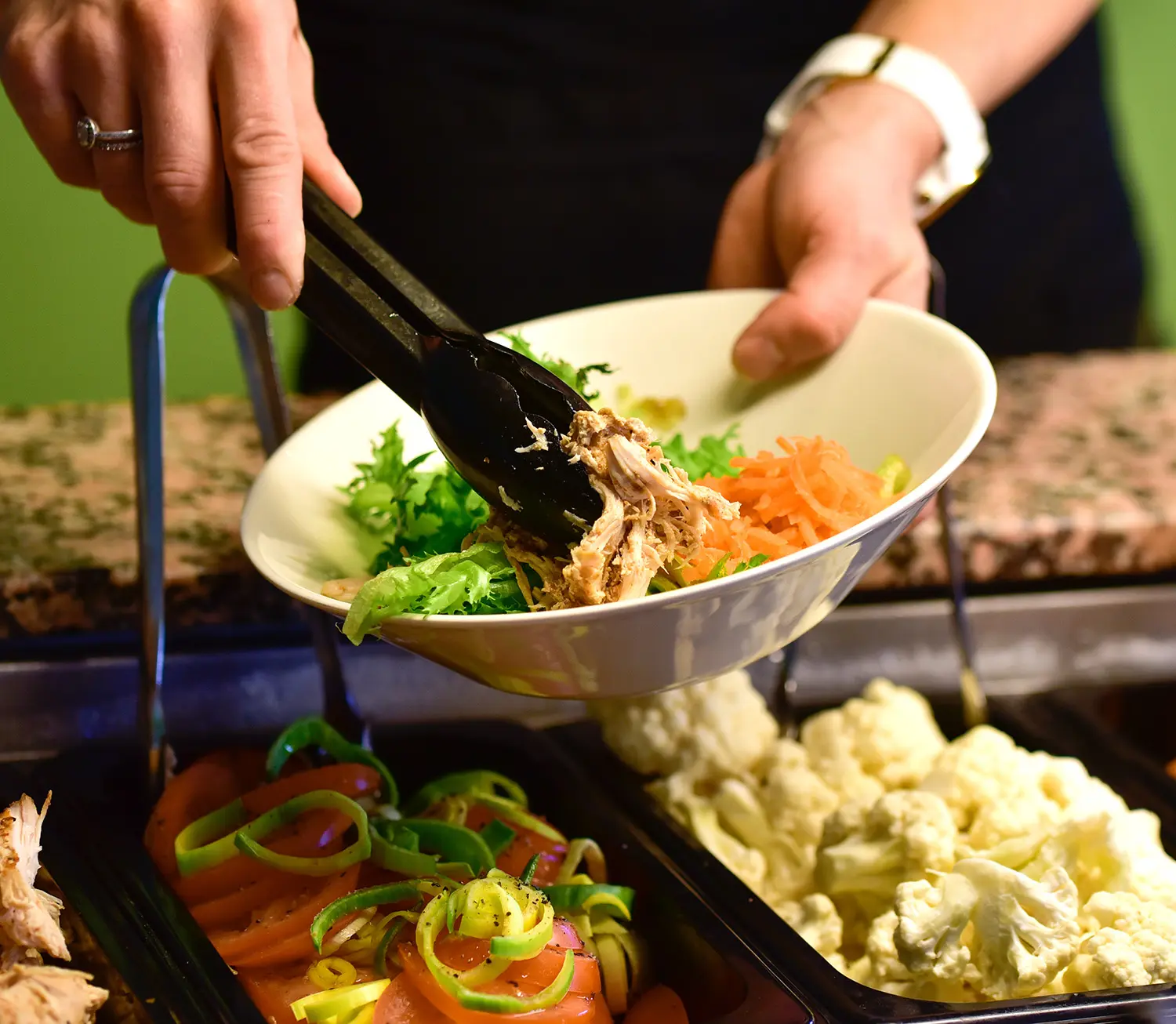 Nainen ottamassa salaattia buffetissa