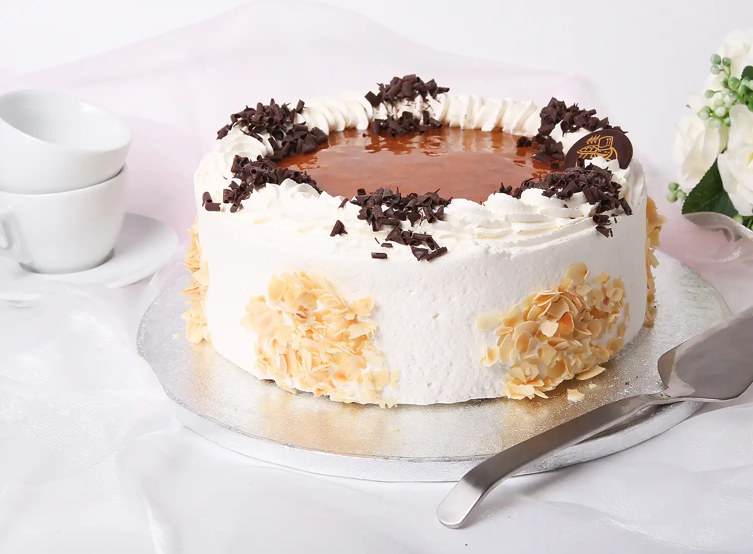 Kermalla koristeltu lakkatäytekakku hopeisella alustalla