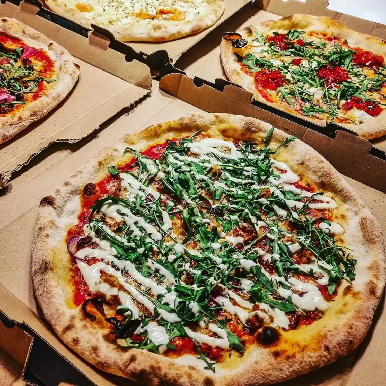 Neljä pizzerian pizzaa pöydällä