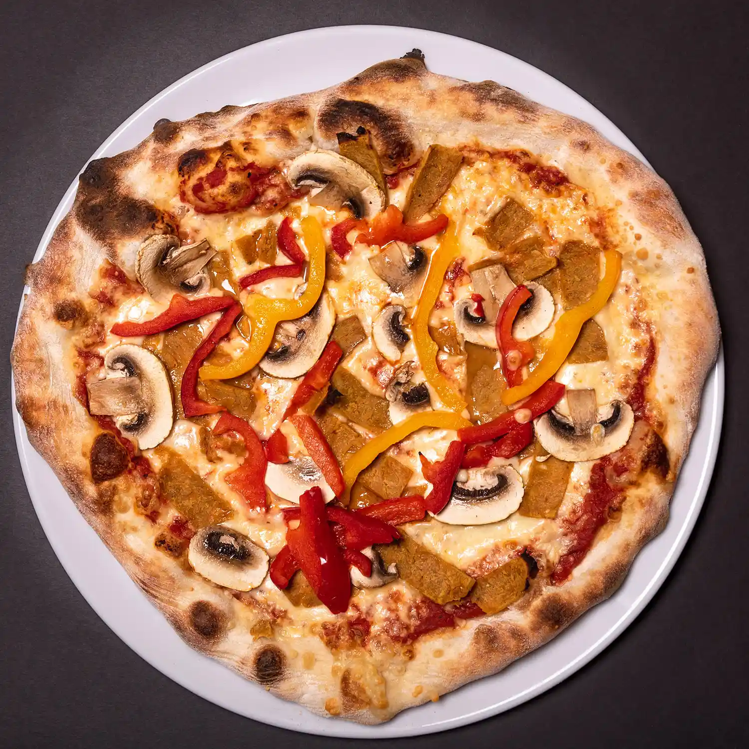 Seitan-lastuilla, paprikalla ja herkkusienillä täytetty artesaanipizza lautasella